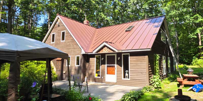 Seamless gutters installed on a red standing seam metal roof, project photo 1