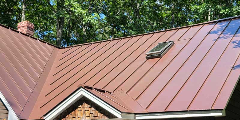 Seamless gutters installed on a red standing seam metal roof, project photo 2
