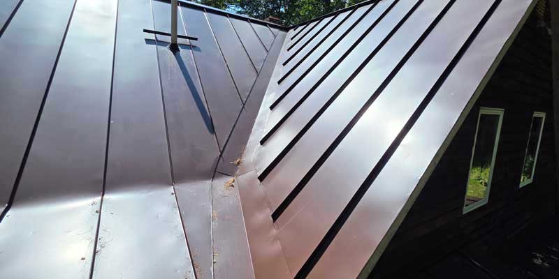 Seamless gutters installed on a red standing seam metal roof, project photo 7
