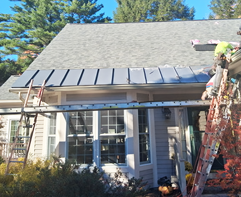 LaVorgna Construction crew installing a charcoal standing seam metal snow belt along the eave of a New Hampshire home